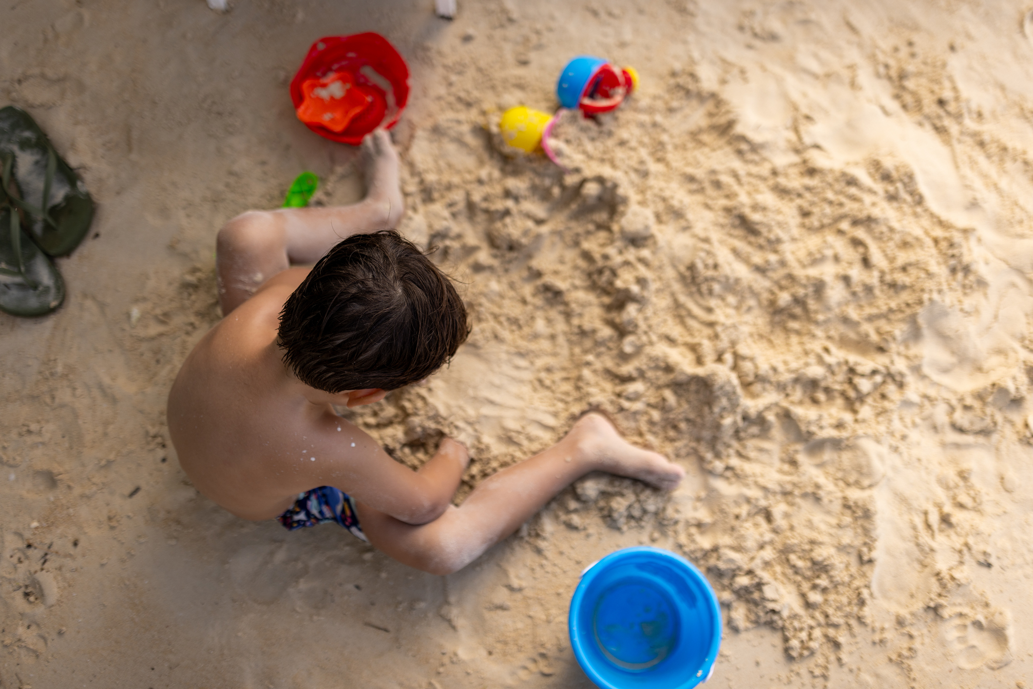 Children playing in a large indoor sandbox, exploring and creating with sand toys.