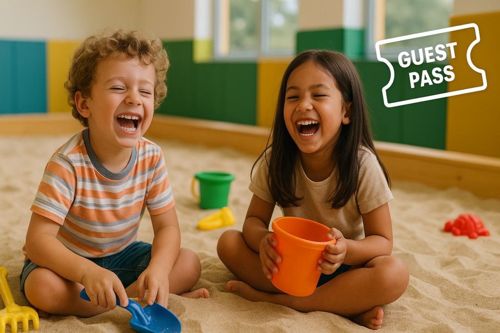 Two kids laughing while playing in the sand in an indoor sandbox playground, with a ticket icon representing a guest pass.