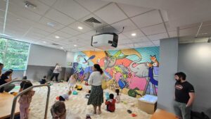 A group of children socializing comfortably whiles playing together in a clean and safe sandmagination's indoor sandbox playground with grafiti painted walls.