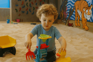 A child in a sandbox confidently selecting tools while playing in the sand, showing concentration and joy