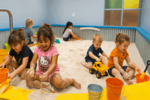 kids playing happily and getting messy in the sand in an indoor sandbox playground.
